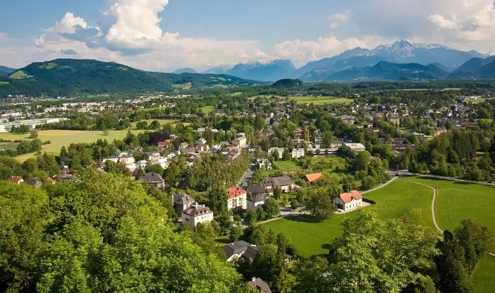 Wohnhäuser in einem grünen Tal vor Alpenpanorama